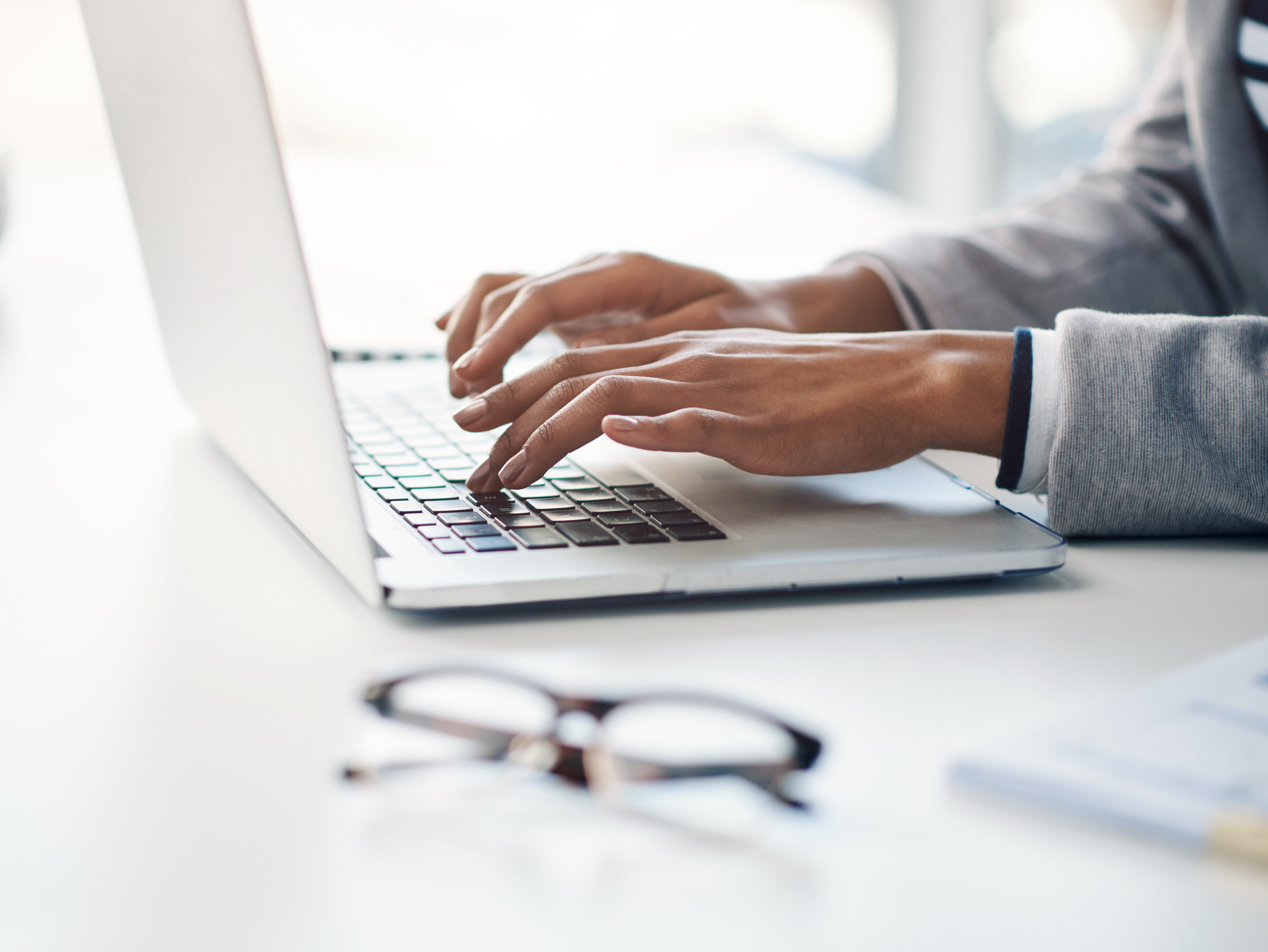 Office, typing and hands of woman at laptop for research, business review or online report at agency. Budget, planning and consultant at desk with computer, networking and financial risk management